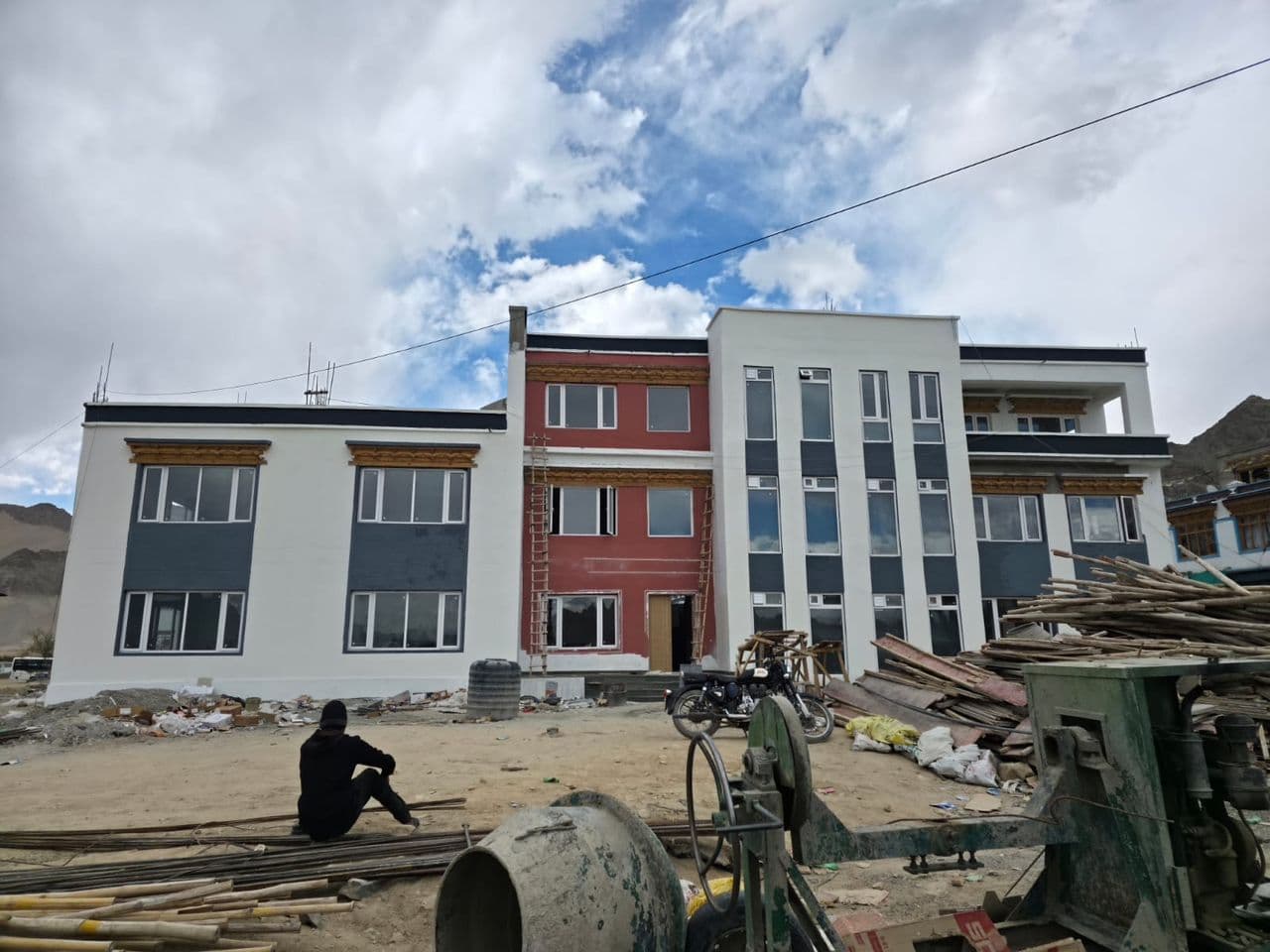 The Centre of Excellence, a three-storey white, grey and red building with Ladakhi-style window cornices, nearing completion