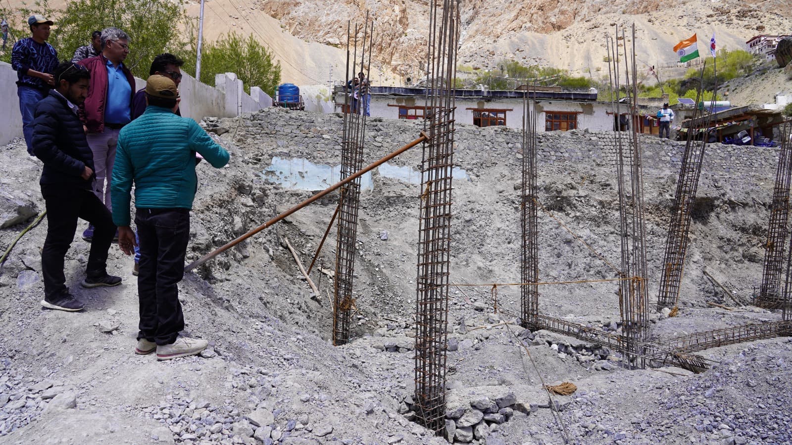 Members of the monitoring team reviewing the reinforced foundation of a new school building on site