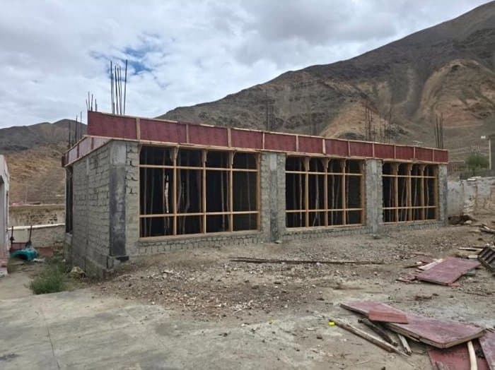 A row of new classrooms under construction, with timber and building material on the ground in front