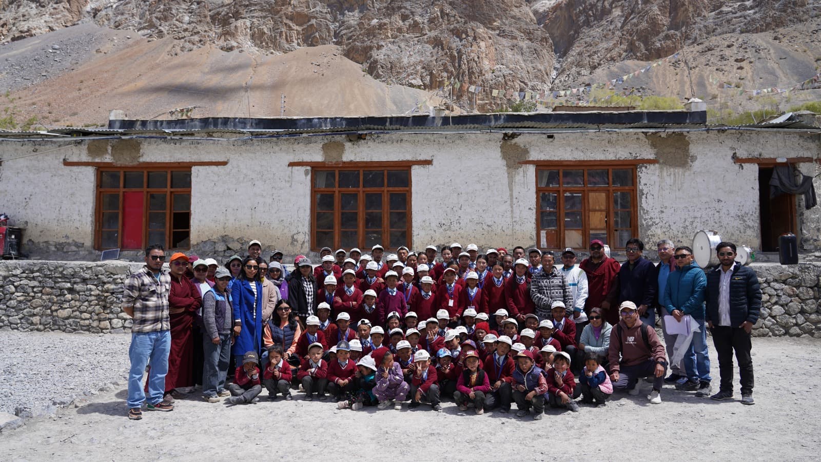 The monitoring team with students and staff assembled outside a school during the visit