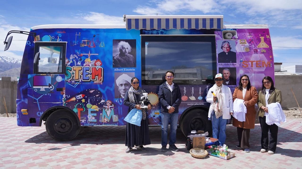 The Mobile STEM Bus, painted with images of scientists, with DIET Leh's STEM team standing in front of it