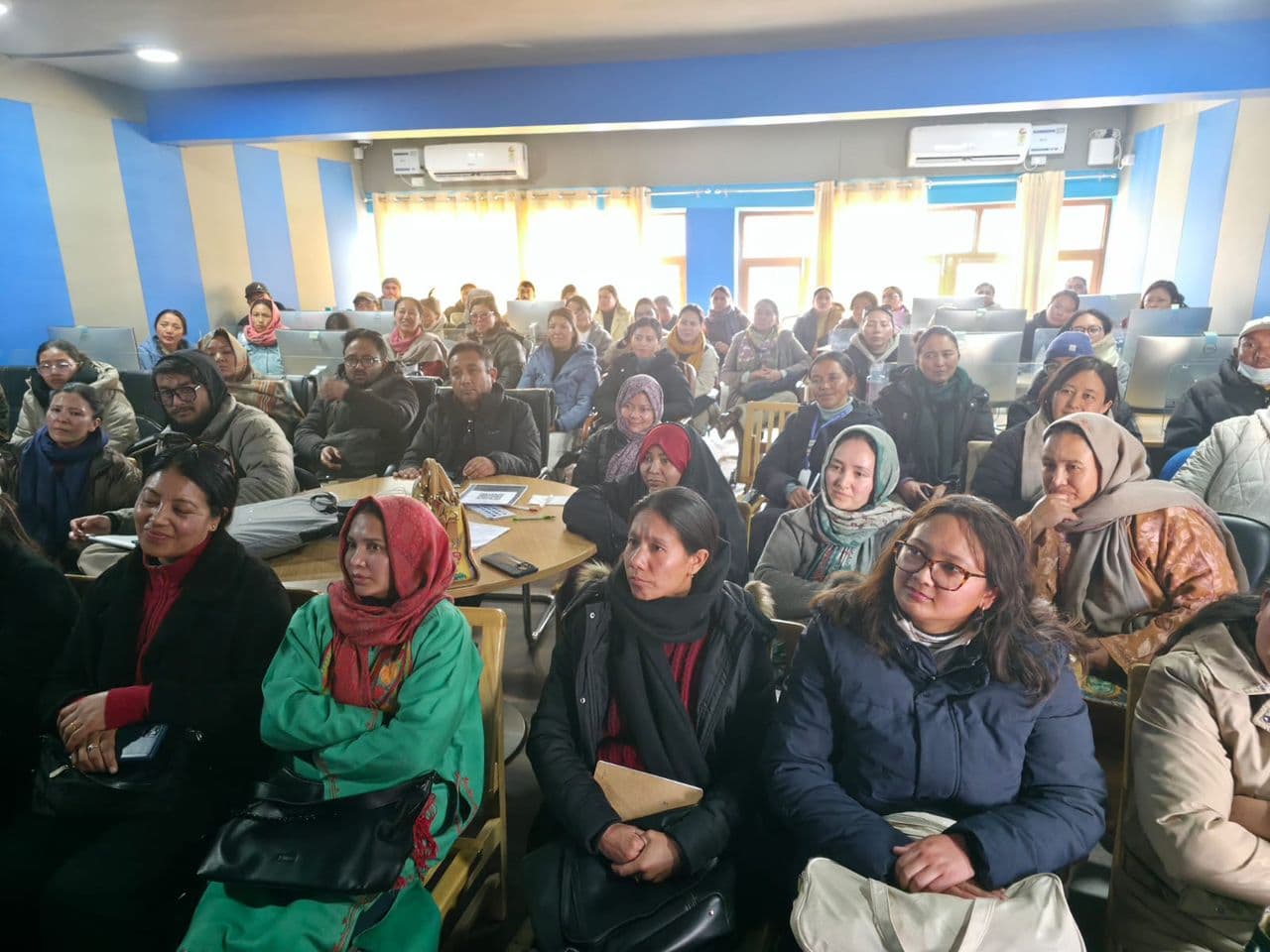 Teachers seated among the computer workstations of the Vidya Samiksha Kendra, facing the front